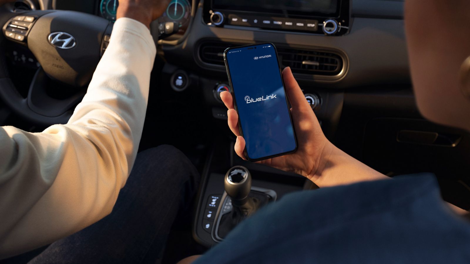 A person is holding a cell phone in their hand while driving a car.
