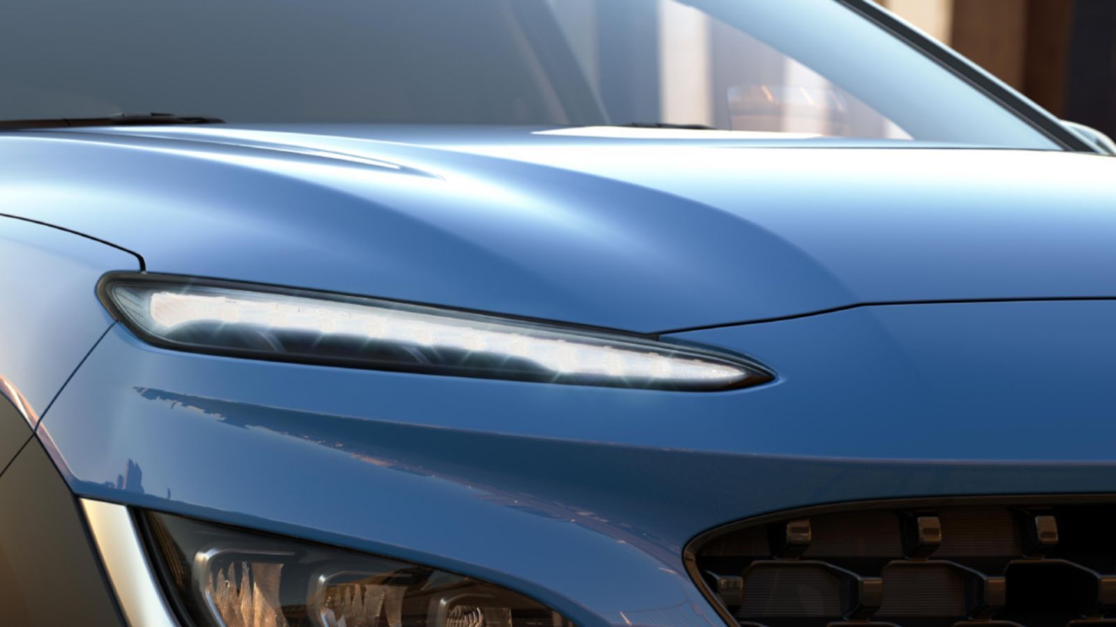 A close up of a blue car 's hood and headlights.