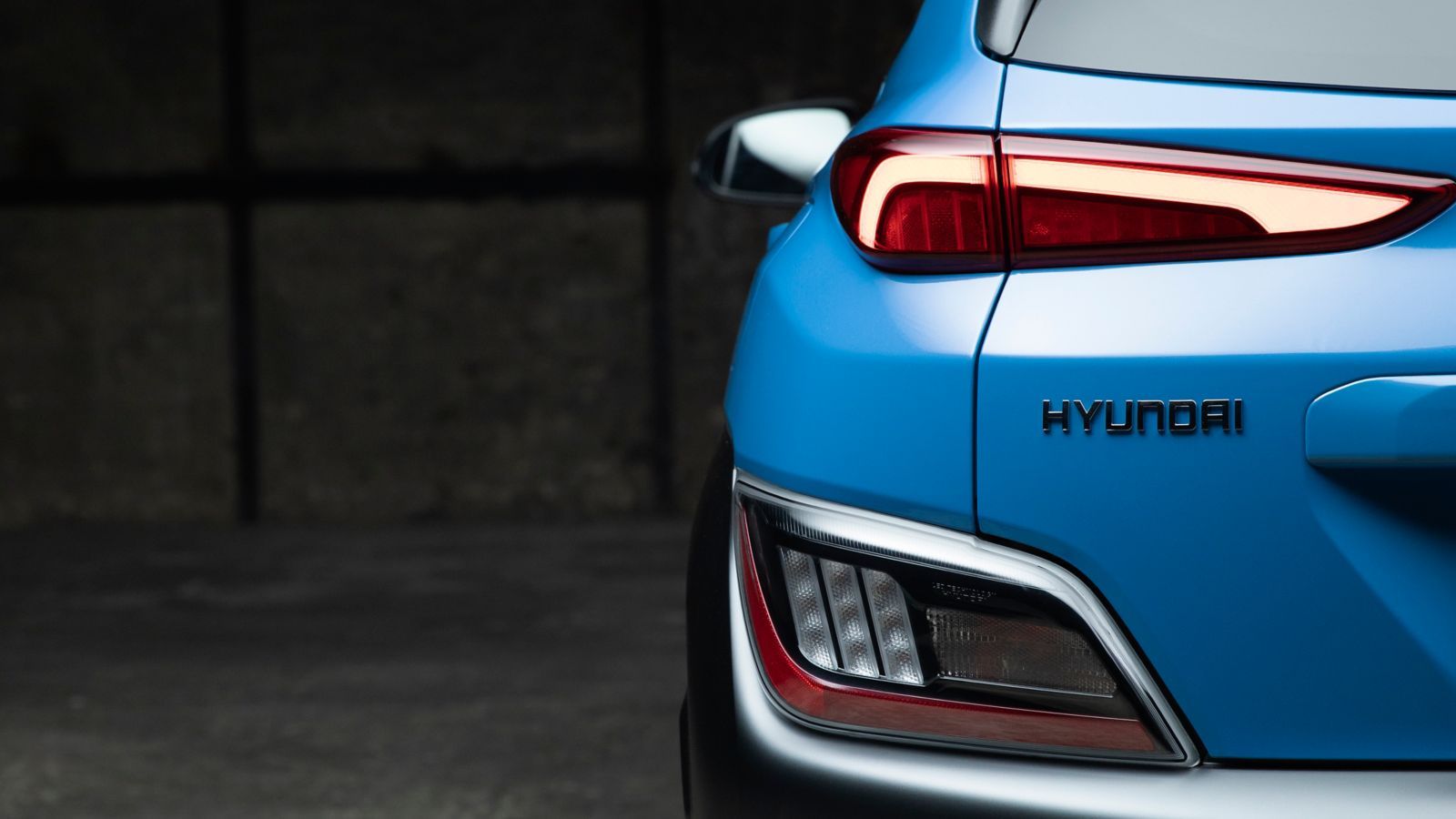 A blue hyundai kona is parked in a dark garage.