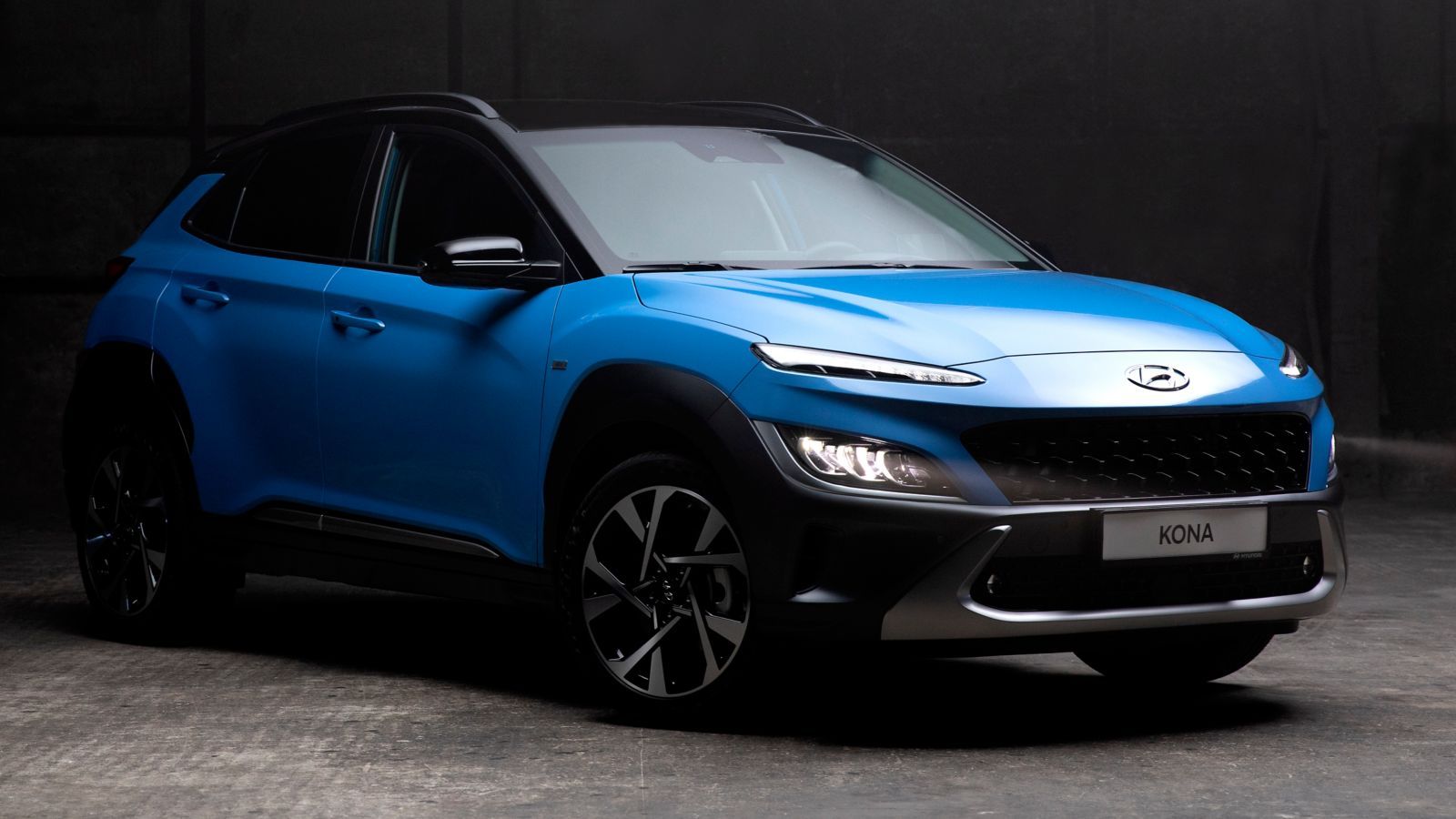 A blue hyundai kona is parked in a dark parking lot.