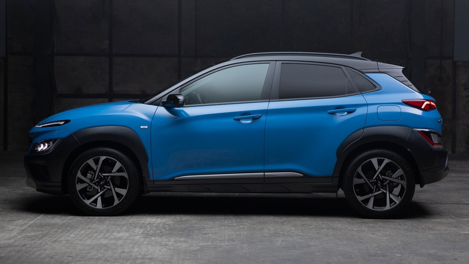 A blue hyundai kona is parked in a dark garage.