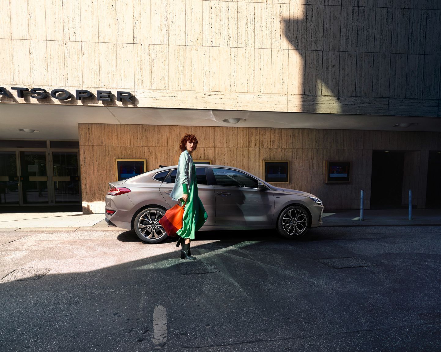 A woman is walking towards a car parked in front of a building.