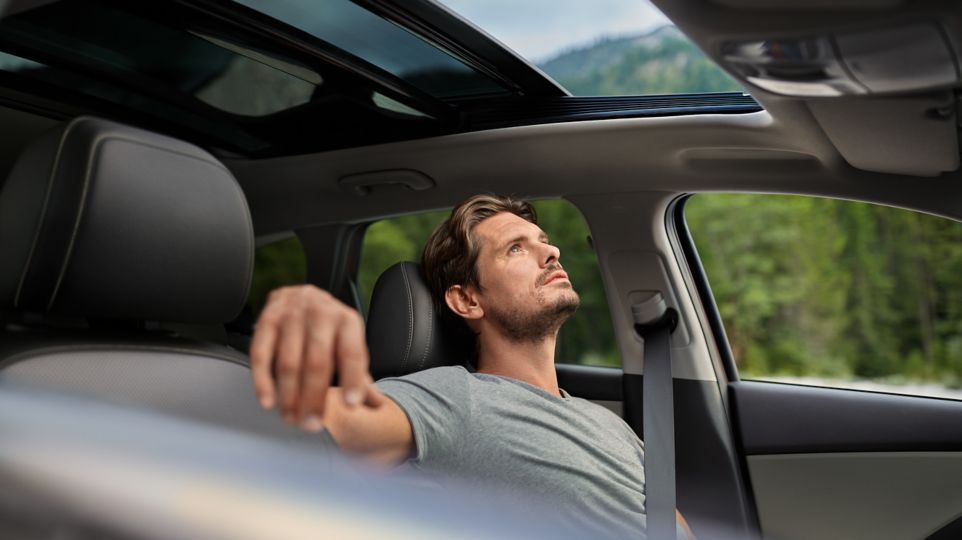 A man is sitting in the driver 's seat of a car with his eyes closed.