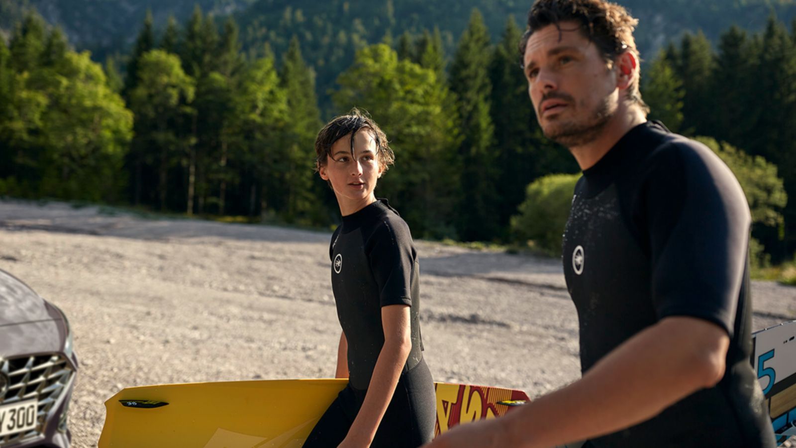 A man and a boy are standing on a beach holding surfboards. i30