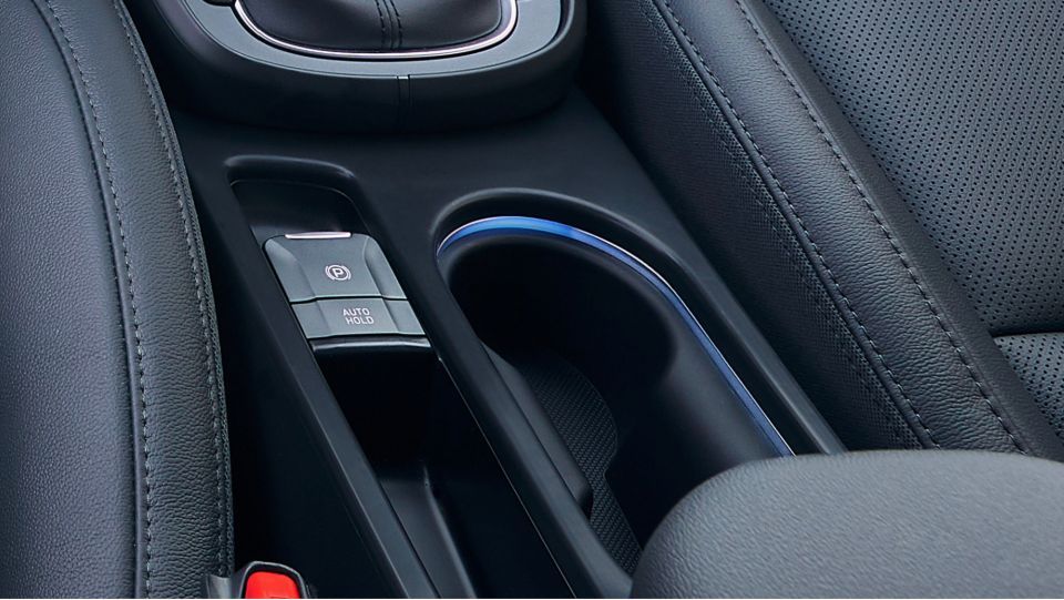 A close up of a car console with a cup holder Kona Hibrid