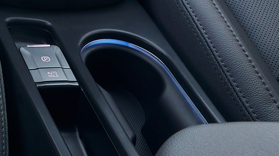 A close up of a car console with a cup holder and buttons.