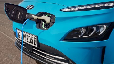The front of a blue electric car is being charged.