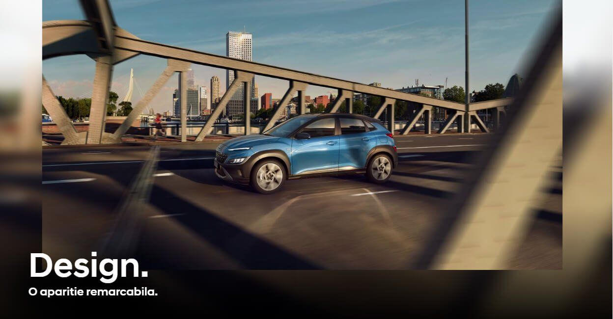 A blue car is driving down a highway under a bridge.