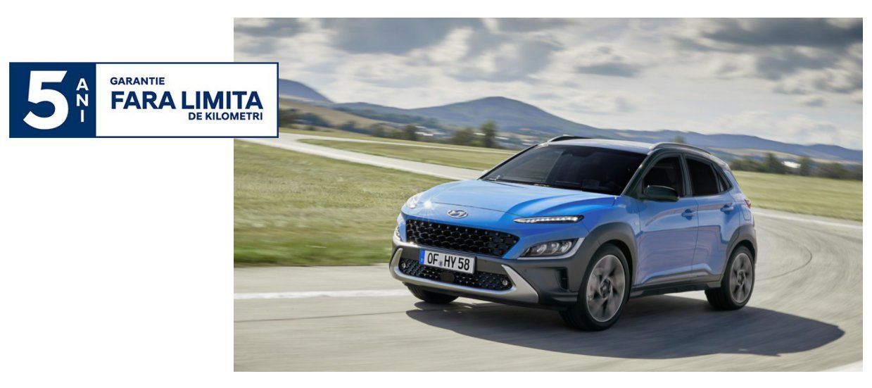 A blue car is driving down a road with mountains in the background.