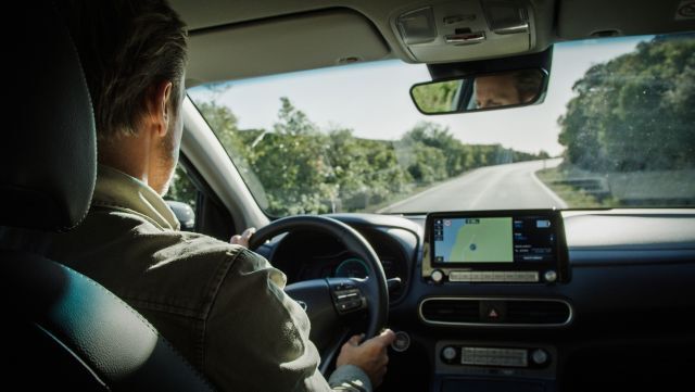 A man is driving a car on a highway.