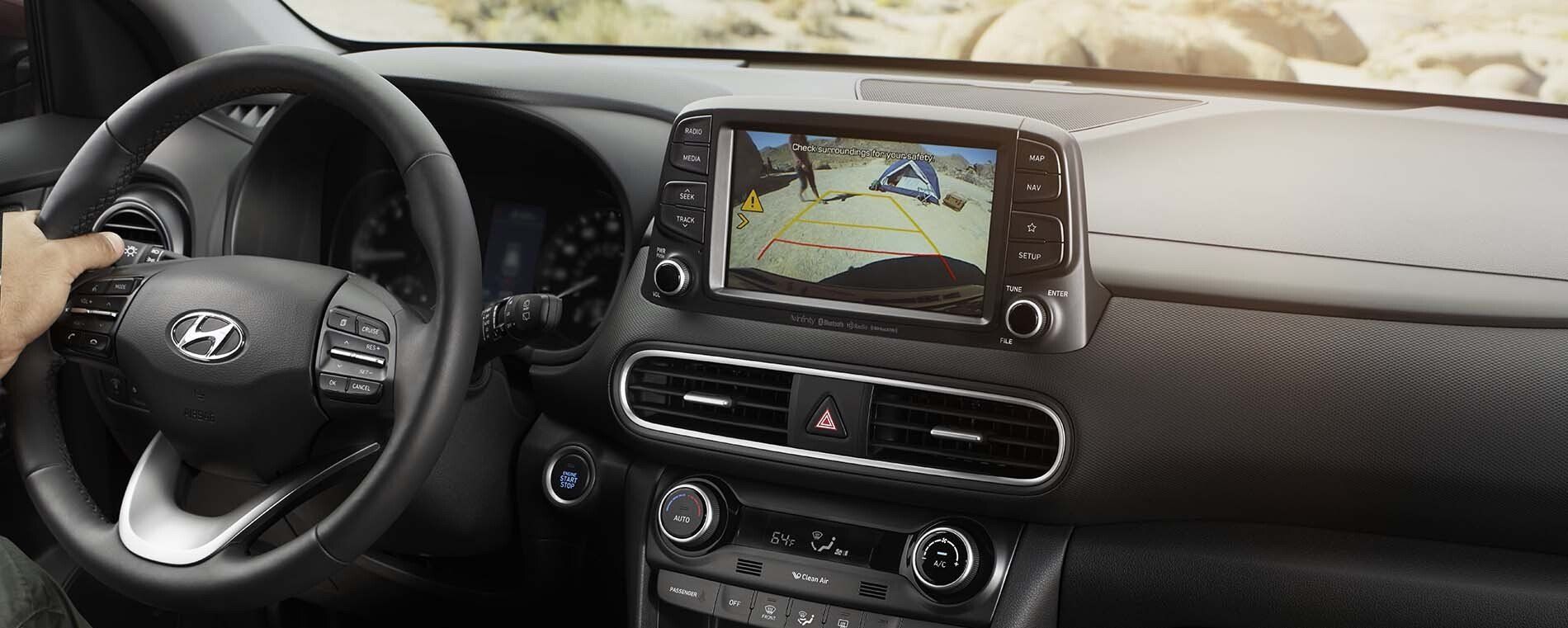 A person is driving a car with a rear view camera on the dashboard.