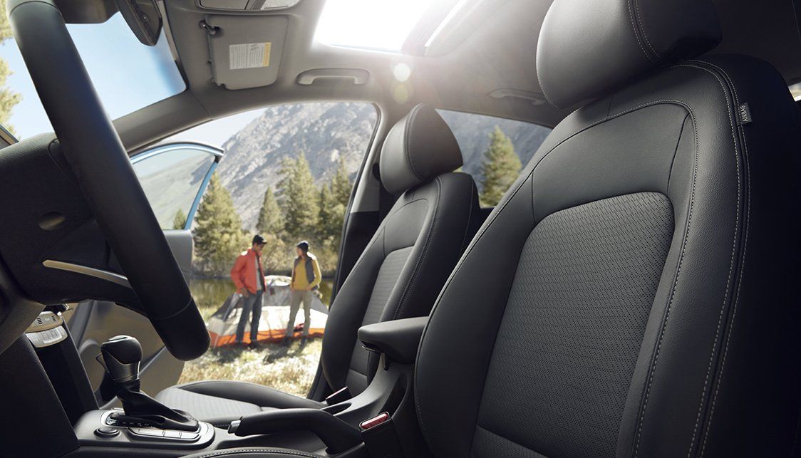 The inside of a car with two people standing in the background.