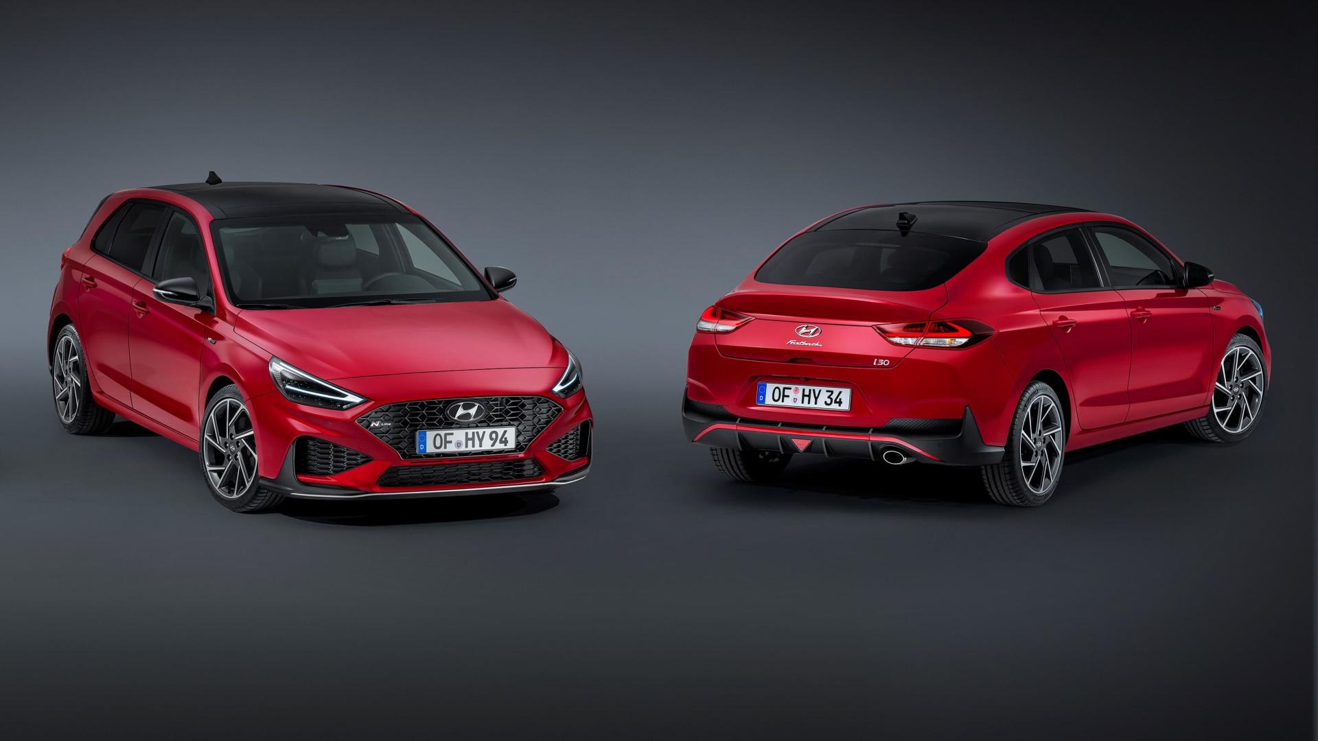 Two red cars are parked next to each other on a black background.