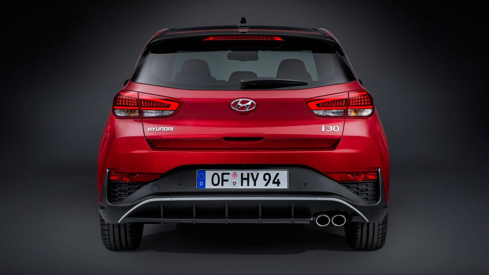 The rear end of a red hyundai i30 hatchback is shown on a black background.