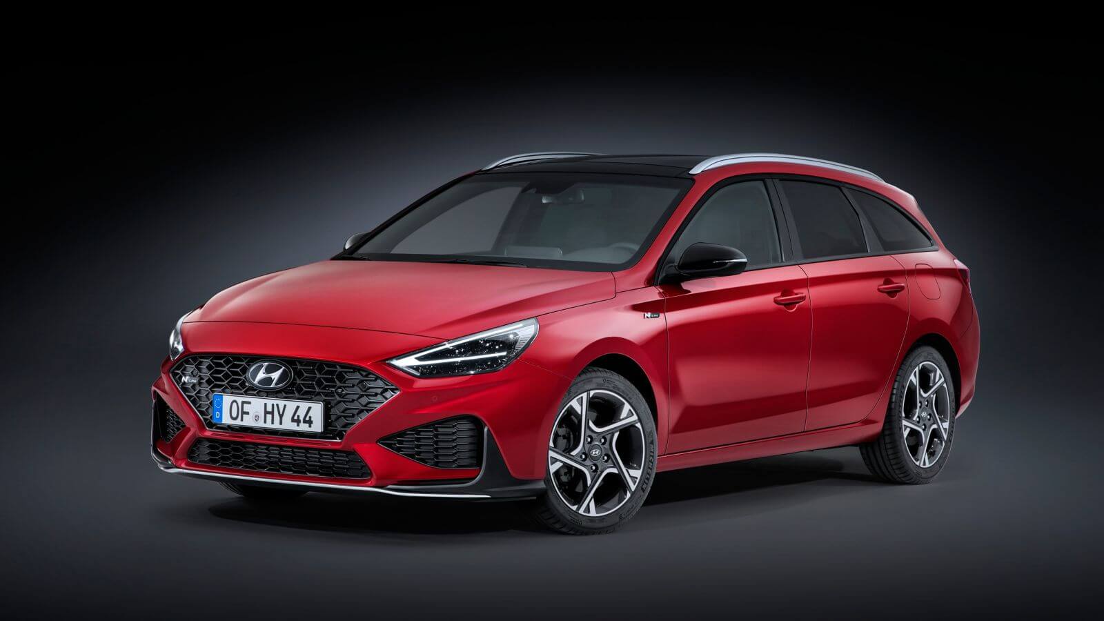 A red hyundai i30 station wagon is parked on a black background.