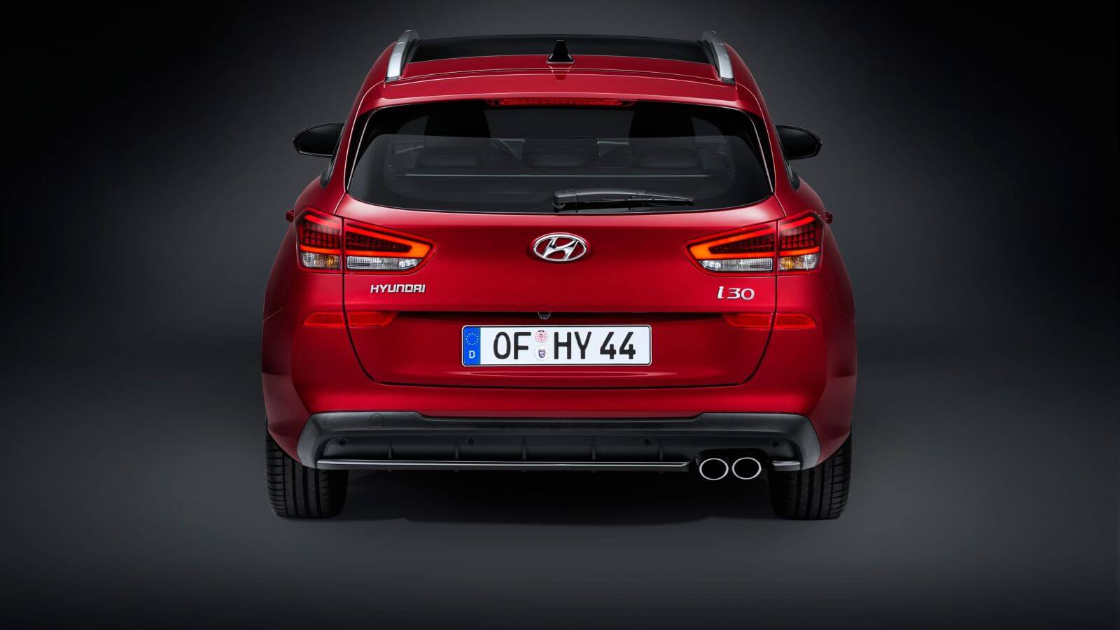 The rear end of a red hyundai i30 is shown on a black background.