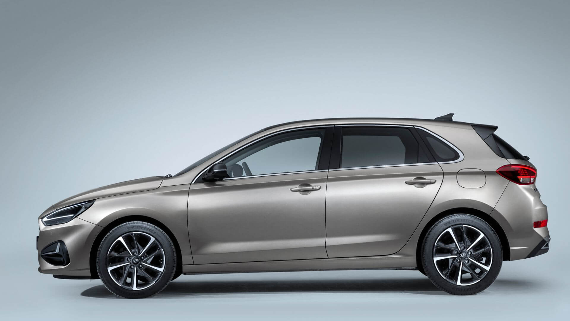 A silver hatchback car is sitting on a blue surface.