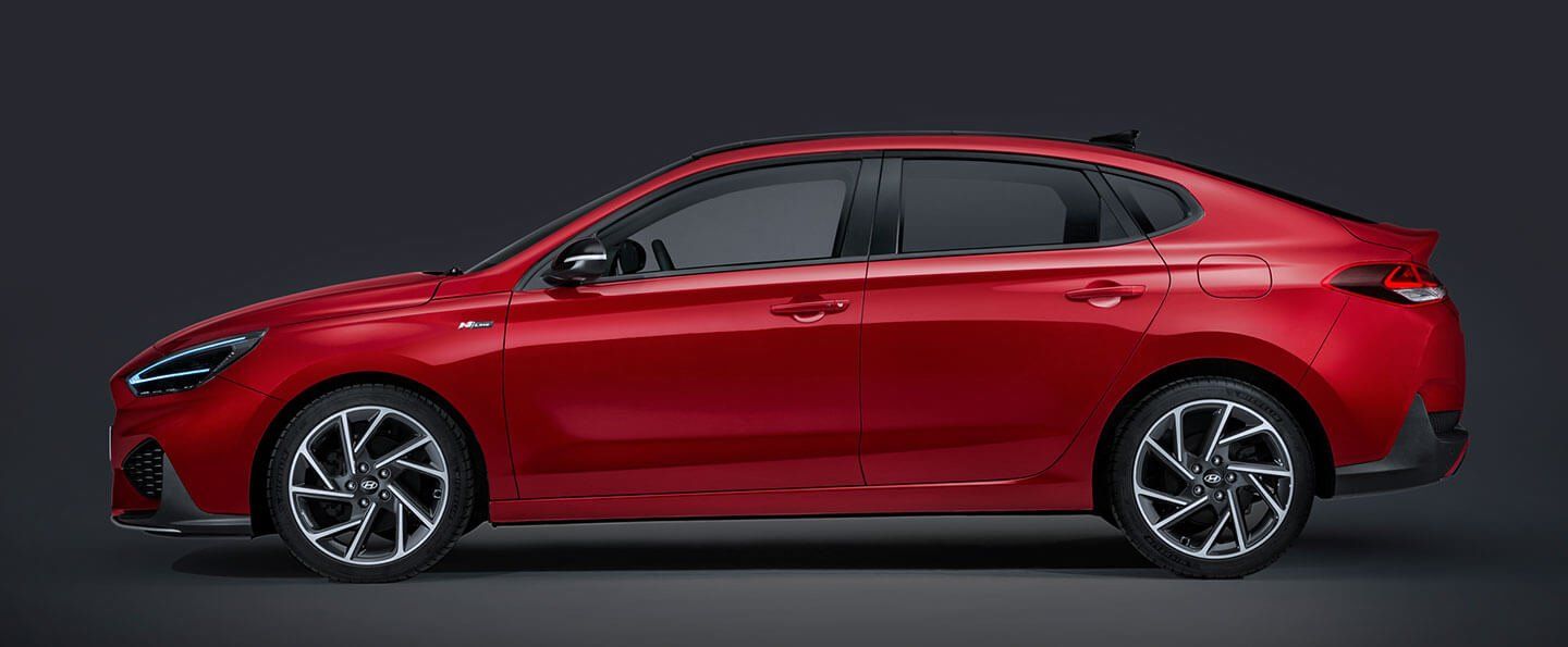 A red car with white wheels is sitting on a black surface.