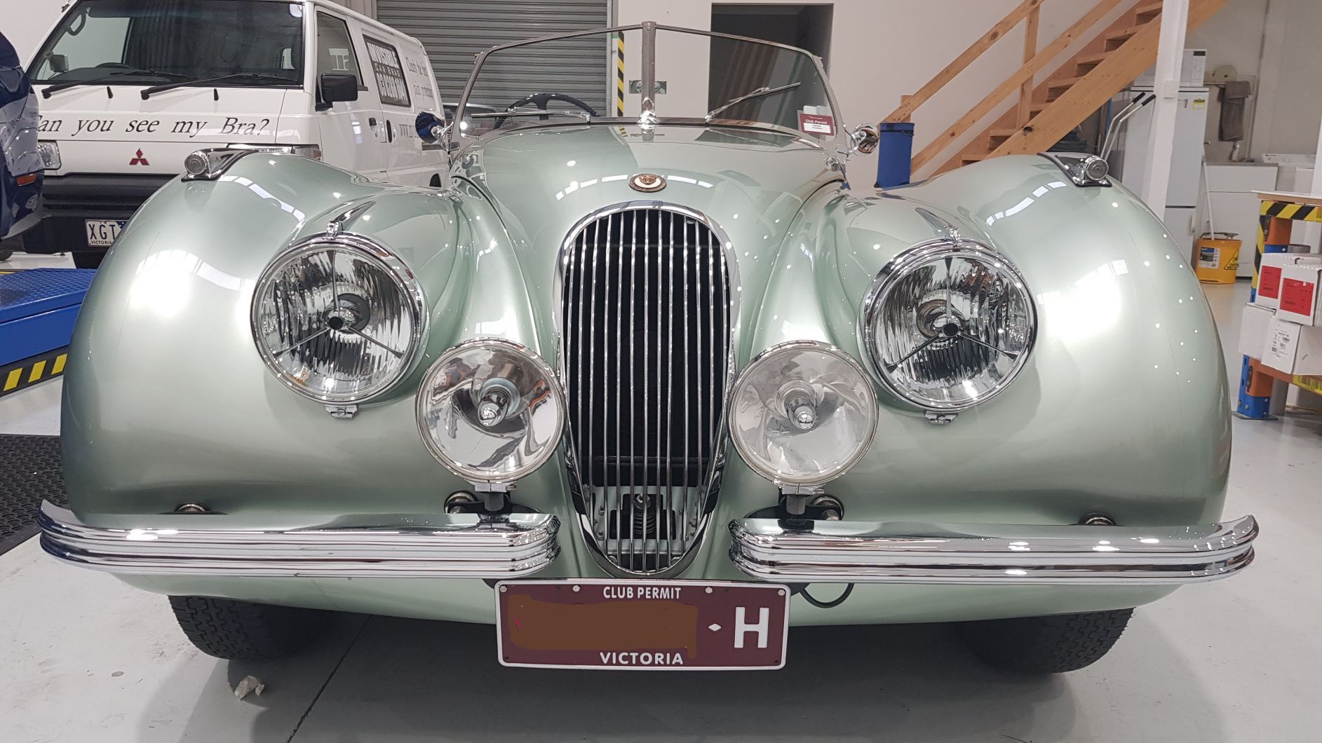 shows the front view of a silver-green Jaguar XK120