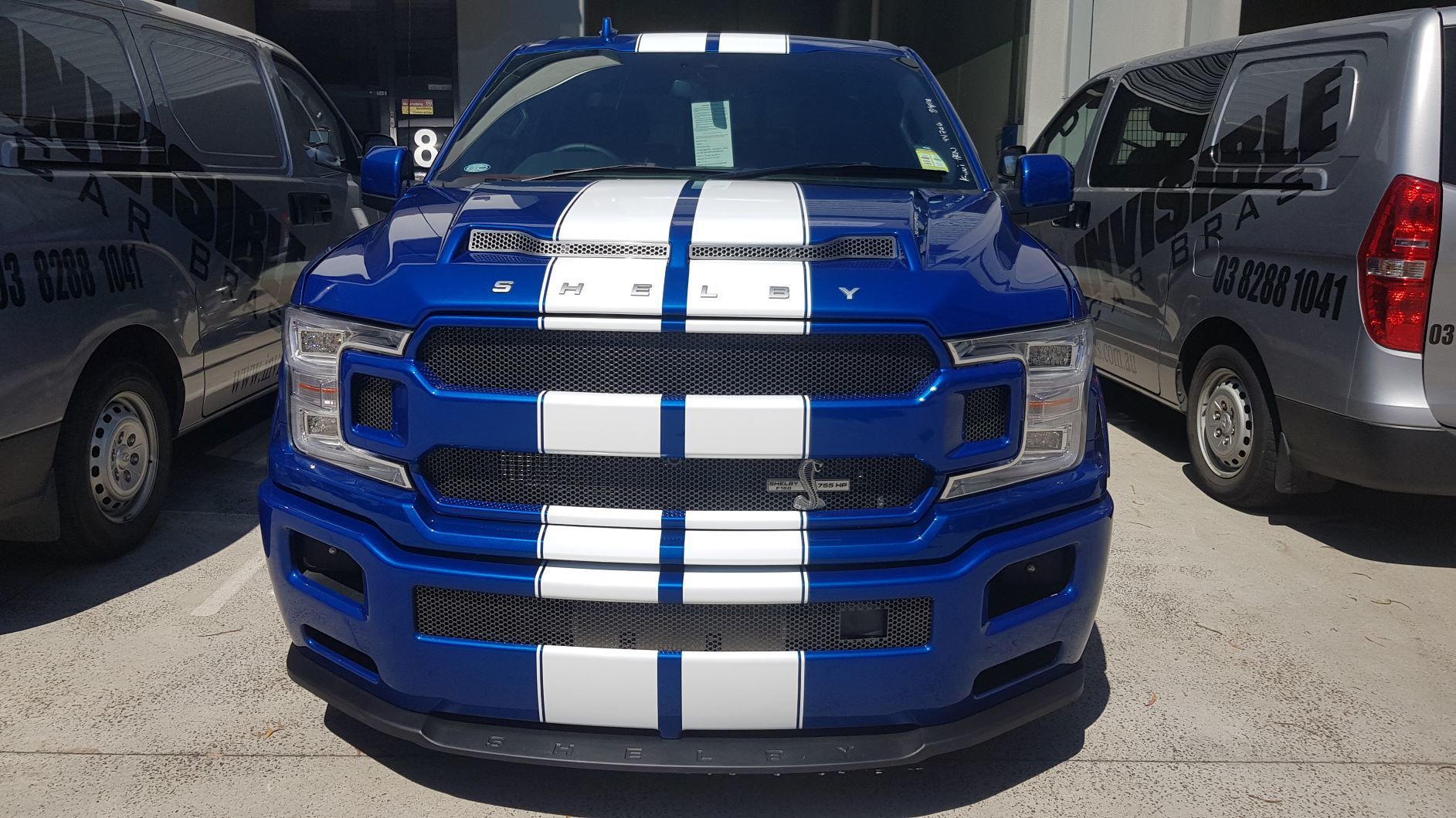  front view of a blue Ford F-150 Shelby Super Snake pickup truck with white racing stripes