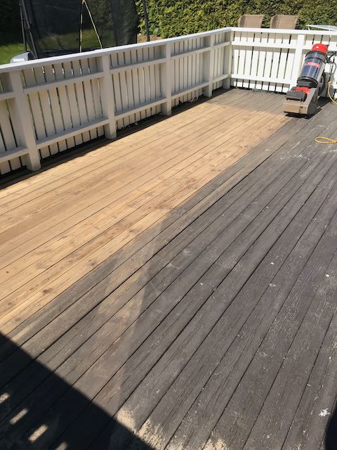En treterrasse som slipes, noe som viser en klar kontrast mellom de mørke, værbitte plankene og det nyslipte lyse treverket.