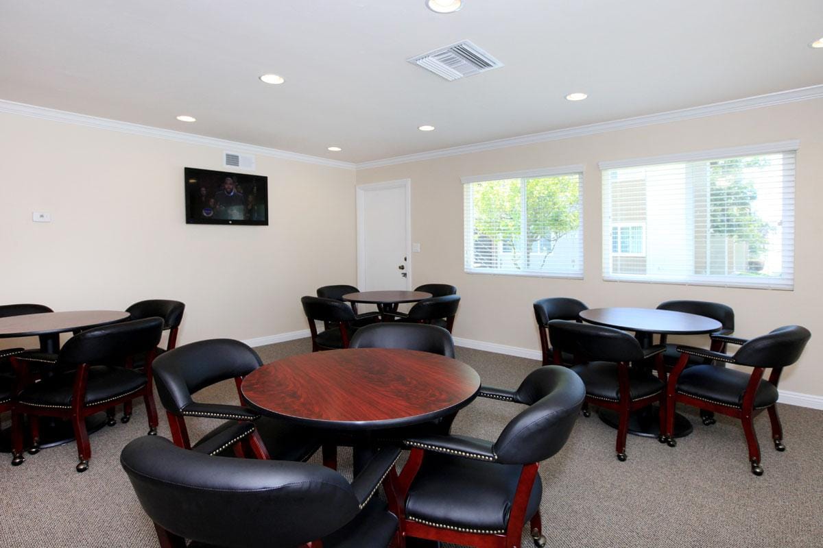 Community room with a full kitchen, tables, and a television.