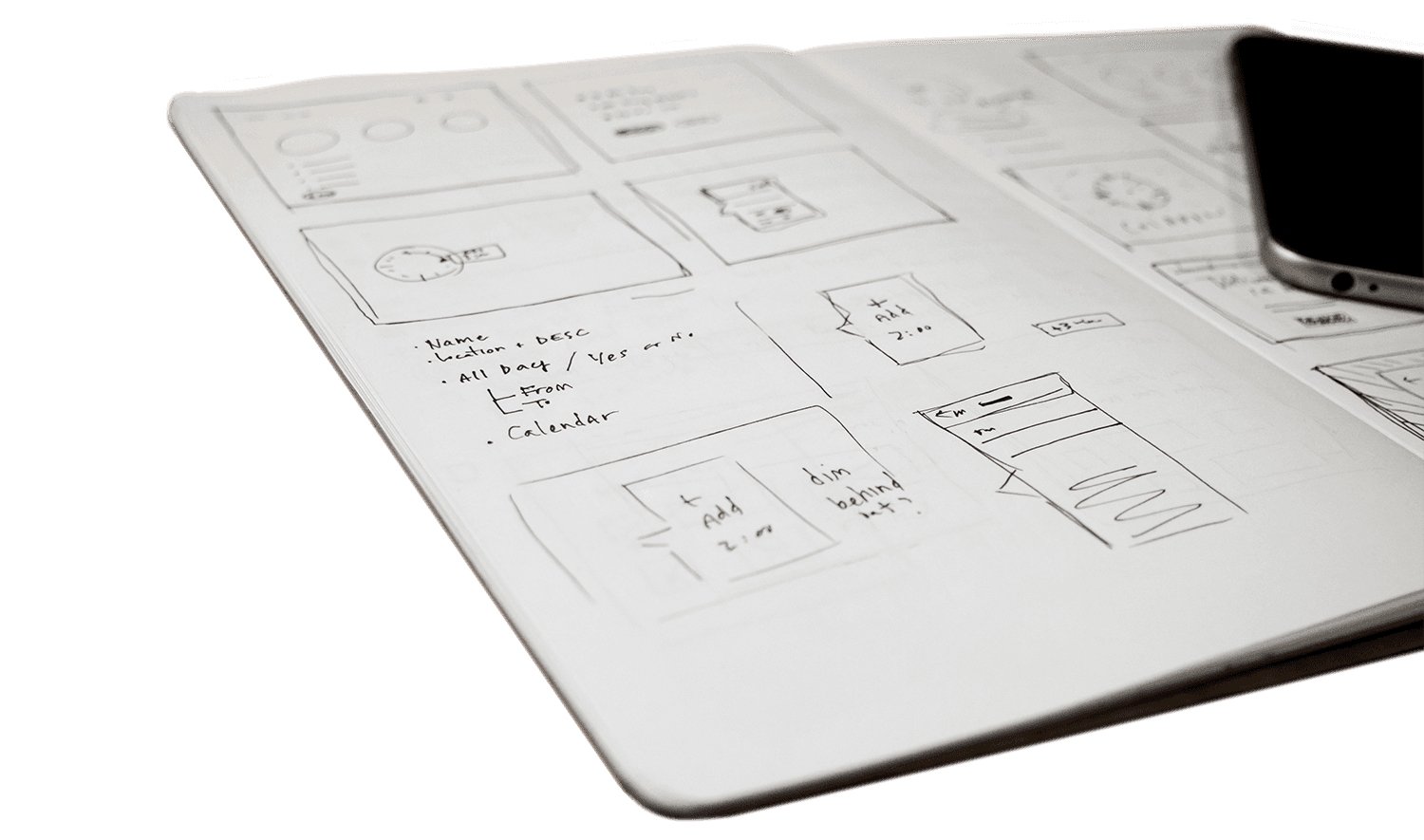 Notebook with sketched website layout and a smartphone on the side.