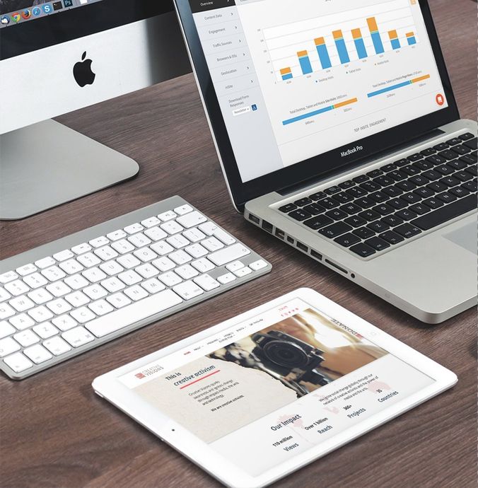 Online Marketing Mac computer, laptop with chart, keyboard, and tablet on wooden desk.