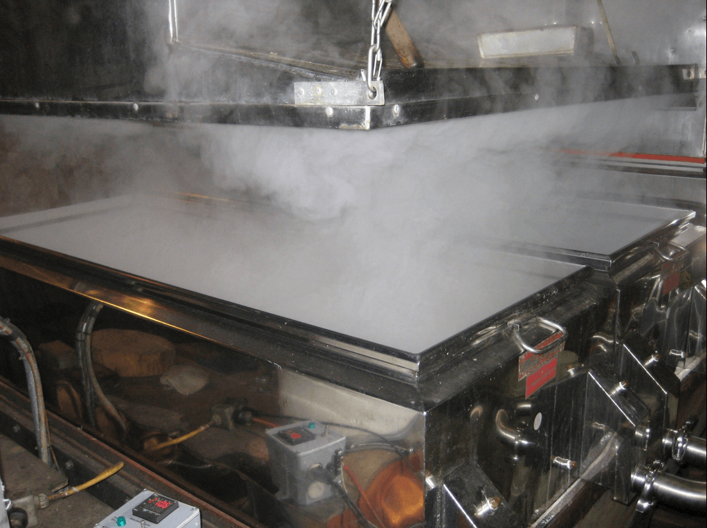 Stainless steel evaporator boiling maple sap, steam rising.
