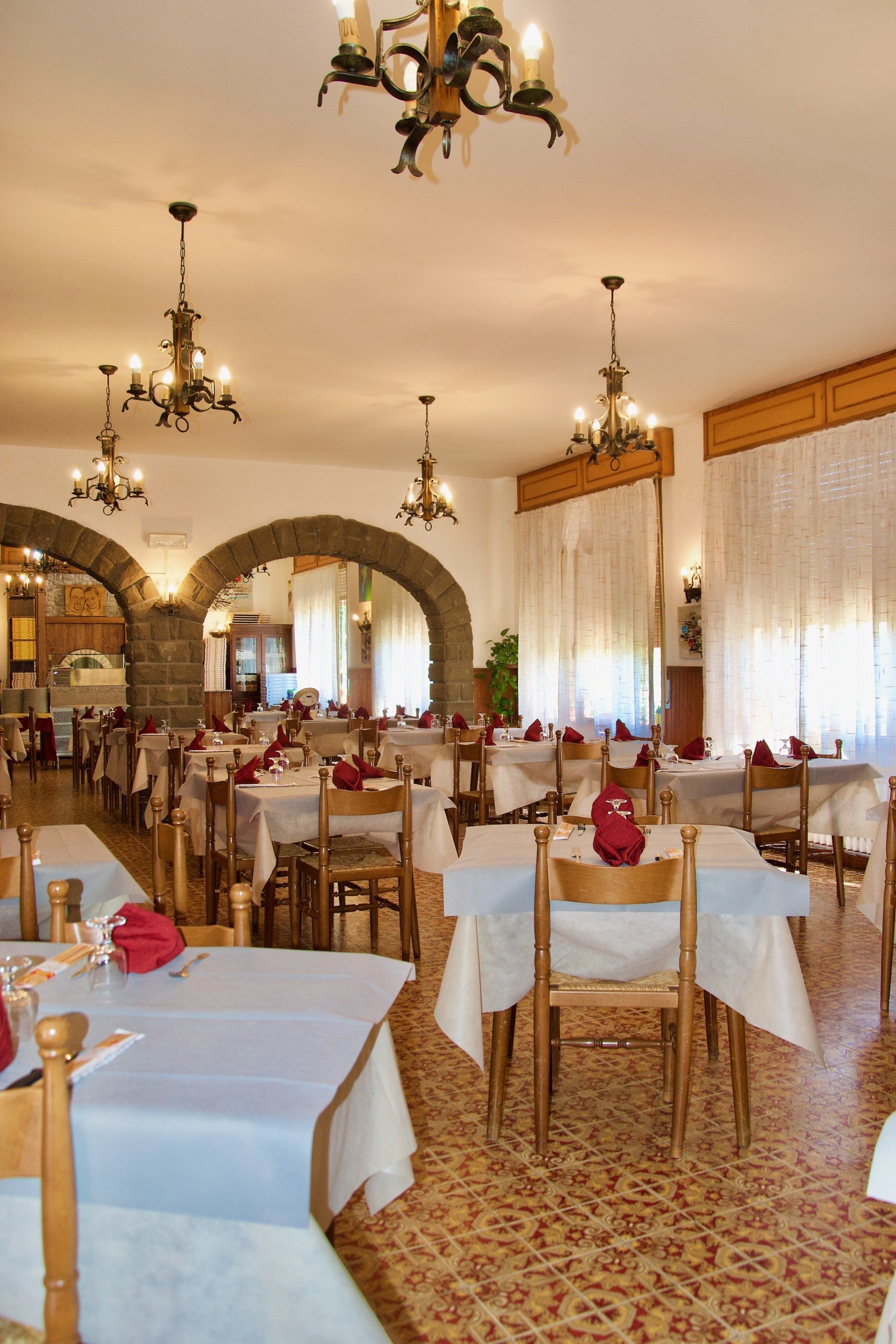 Una sala da pranzo con tavoli e sedie e un lampadario appeso al soffitto