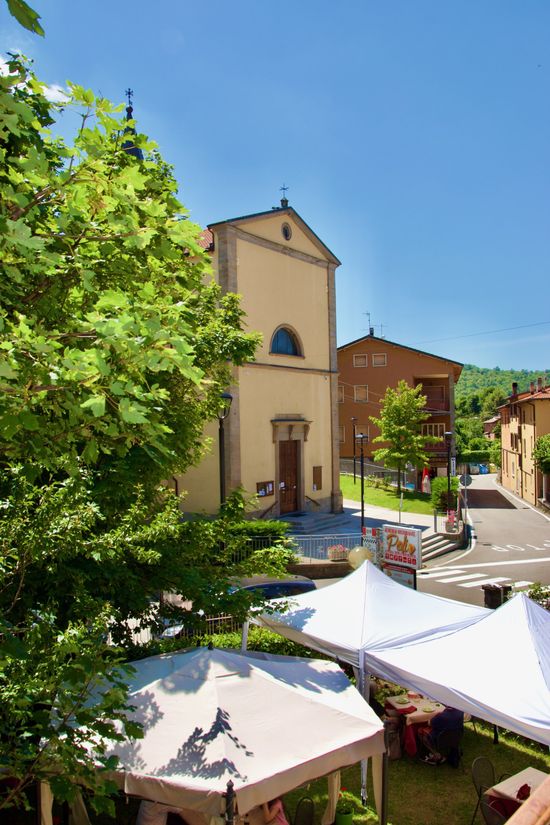Una chiesa è circondata da tende e alberi in una piccola cittadina.