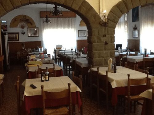 Una sala da pranzo con tavoli e sedie e un arco in pietra