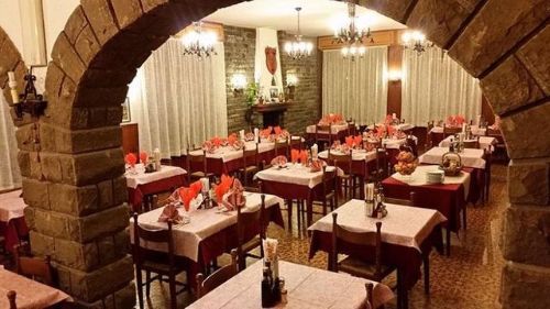 Una grande sala da pranzo con tavoli e sedie e un arco in pietra