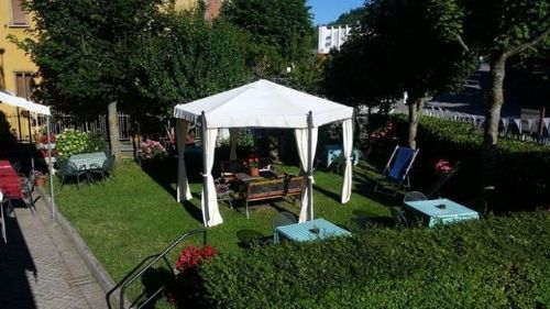 Una tenda bianca è posta in mezzo a un lussureggiante giardino verde.