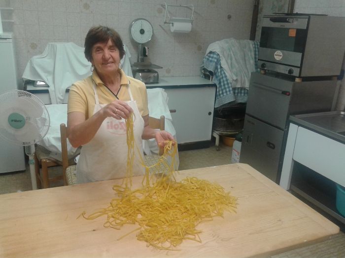 Una donna è in piedi davanti a un tavolo su cui sono serviti i noodles.