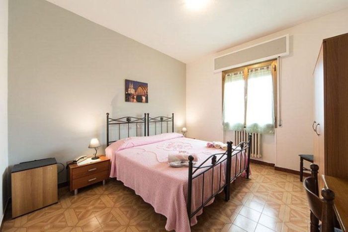 Una camera da letto con un letto king size e due comodini in un albergo con ristorante a Bologna