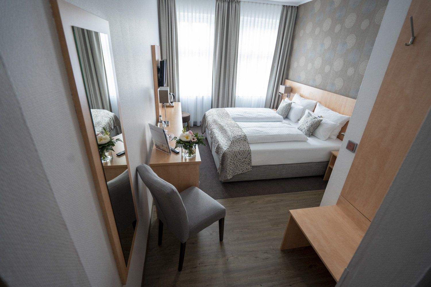 Ein Hotelzimmer mit zwei Betten, einem Stuhl und einem Spiegel.