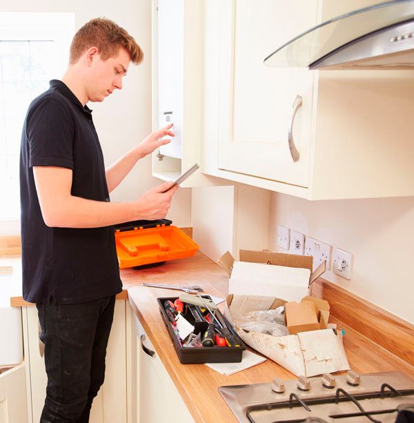 Young technician servicing a boiler, using tablet computer