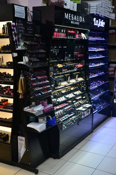 Esposizione di cosmetici con smalti, rossetti e prodotti per il trucco in un negozio.