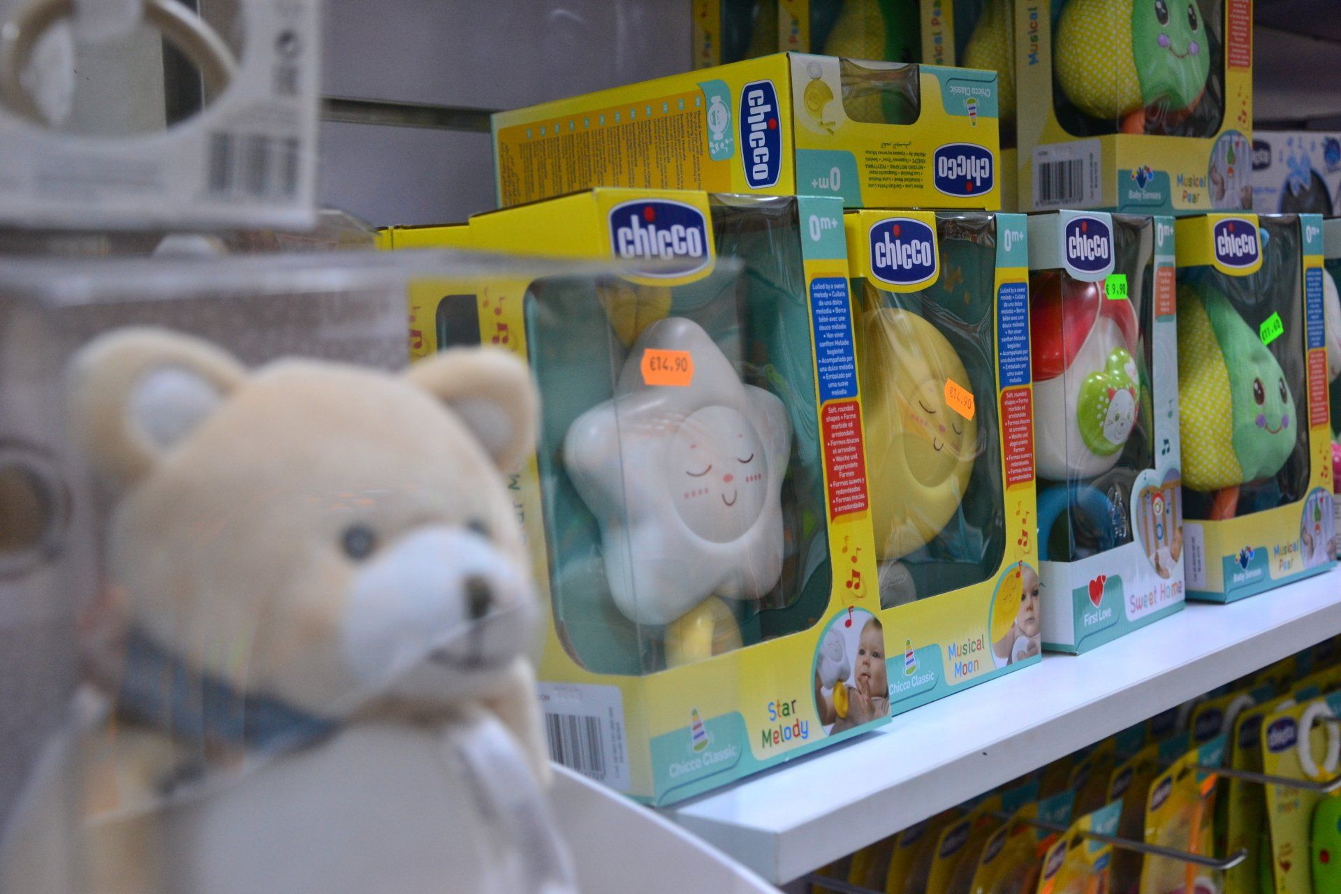 Scaffale di giocattoli per bambini in un negozio. Sono visibili diversi sonniferi Chicco in scatole. Un orsacchiotto è seduto davanti.