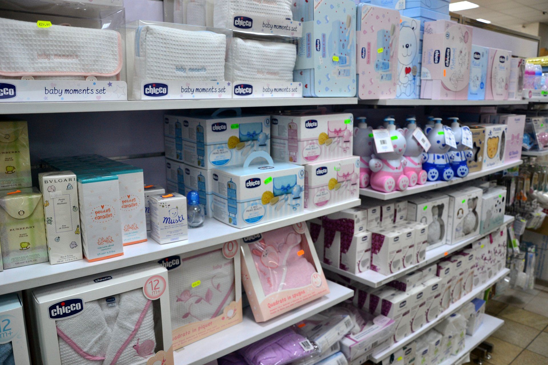 Scaffali pieni di prodotti per la cura del bambino in un negozio; tra gli articoli figurano pannolini, lozioni e vestiti.