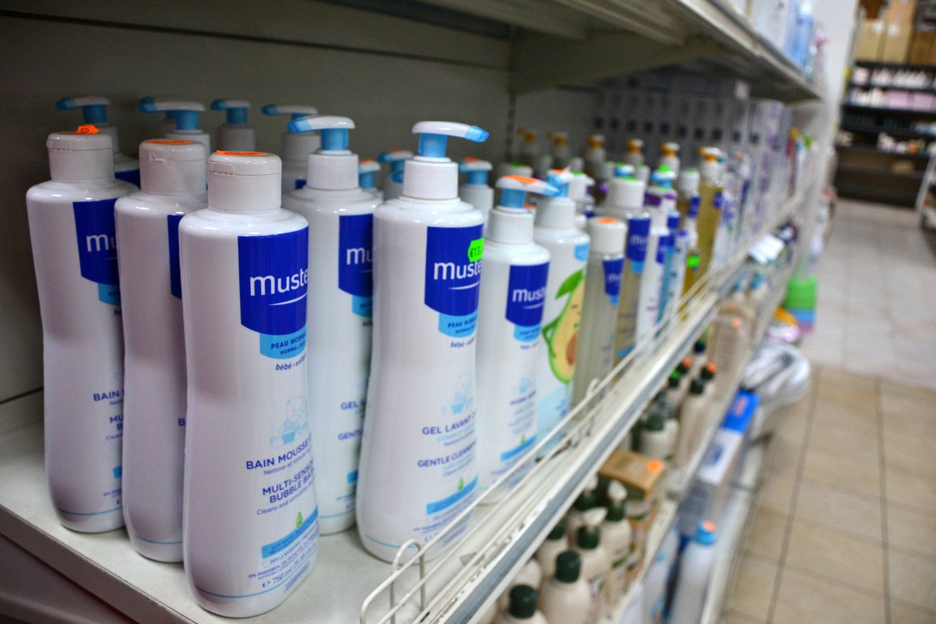 Bottiglie di prodotti per neonati Mustela sullo scaffale di un negozio, etichette bianche e blu.