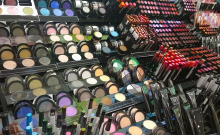 Scaffali pieni di vari ombretti, rossetti e pennelli per il trucco in un negozio al dettaglio.