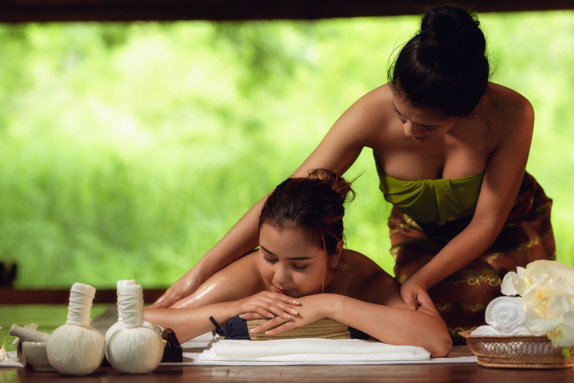 Zwei Frauen geben einer anderen Frau in einem Spa eine Massage.