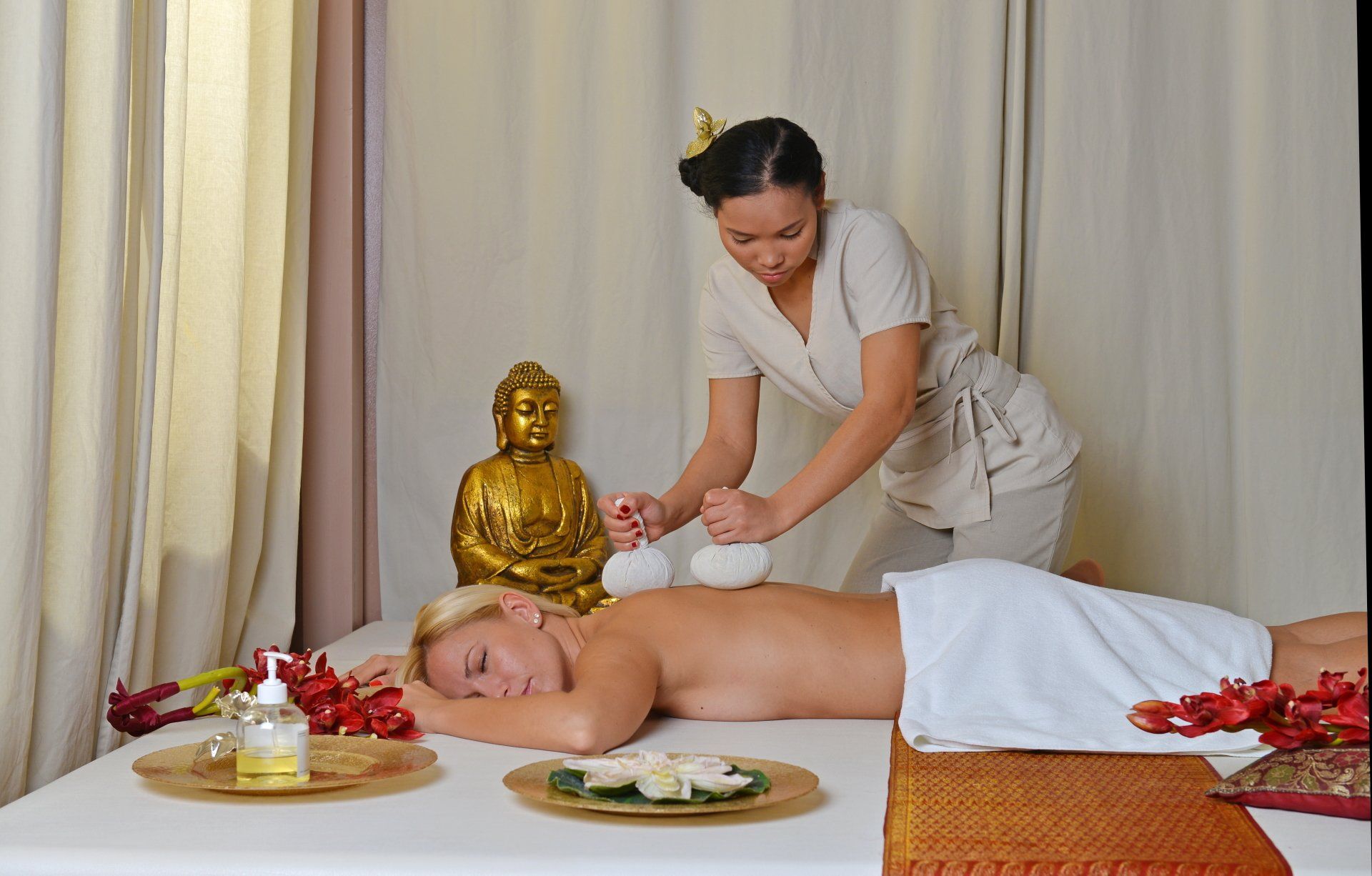 Eine Frau liegt auf einem Tisch und bekommt eine Massage von einem Masseur.