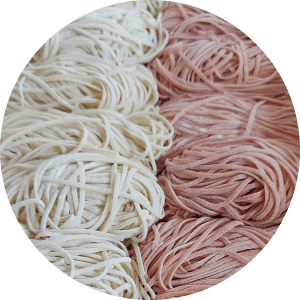 Macarrão fresco branco e rosa em arranjo redondo.