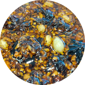 Close de um óleo de pimenta picante com alho, especiarias e anis estrelado visíveis.