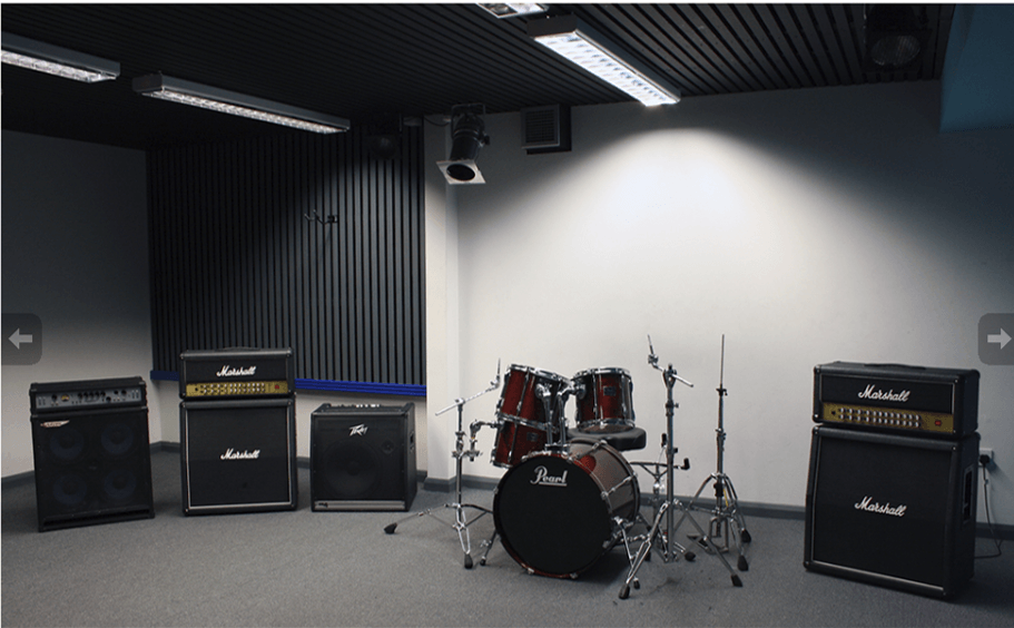 A room with a drum set and a bunch of speakers