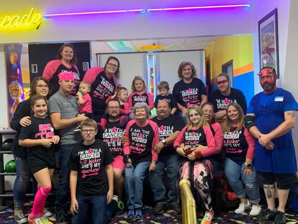 A large group of people are posing for a picture at a bowling alley.