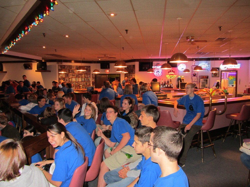 A group of people in blue shirts are sitting in a bowling alley